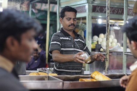 A man standing in front of a counter filled with bread