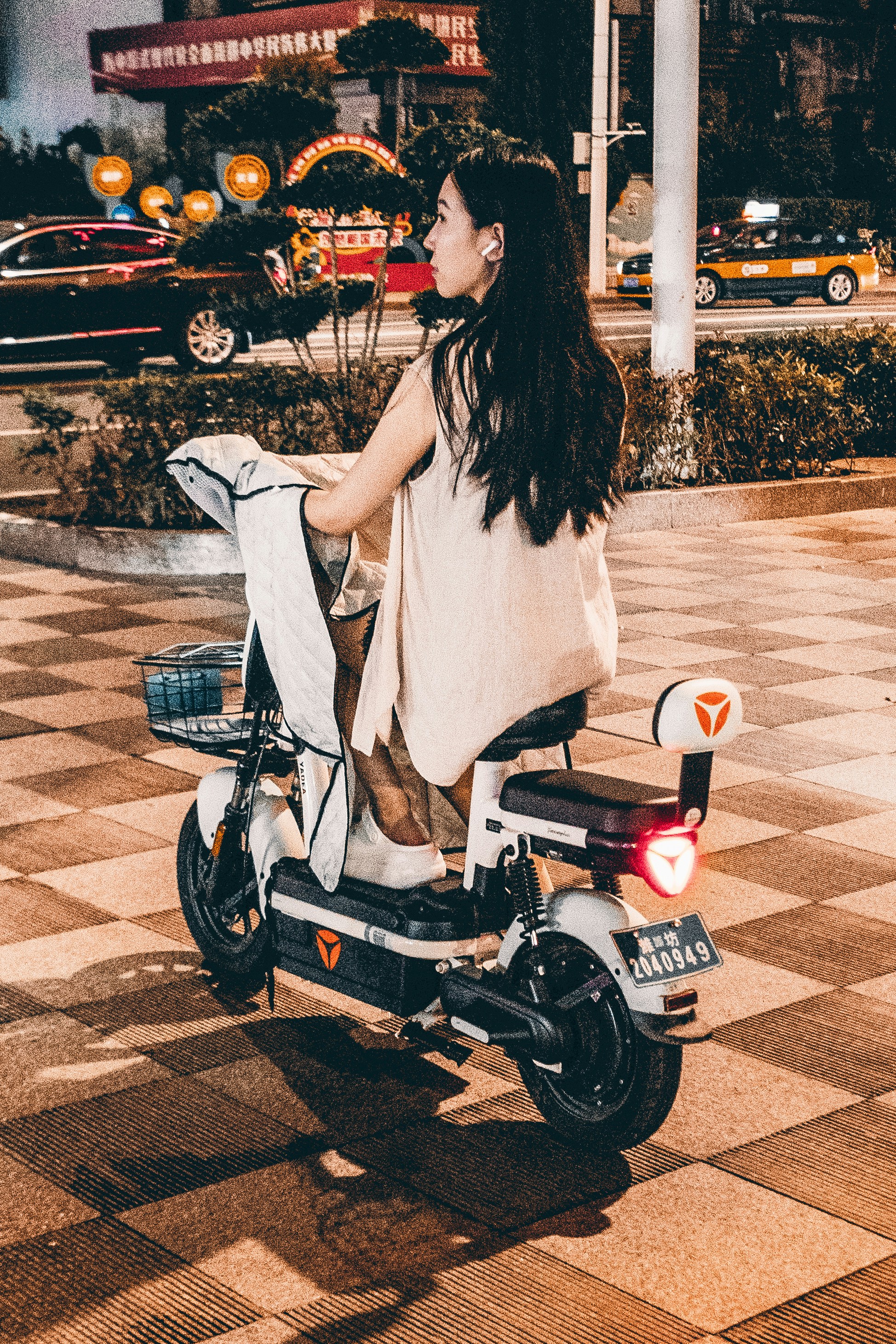 A woman riding a scooter on a city street