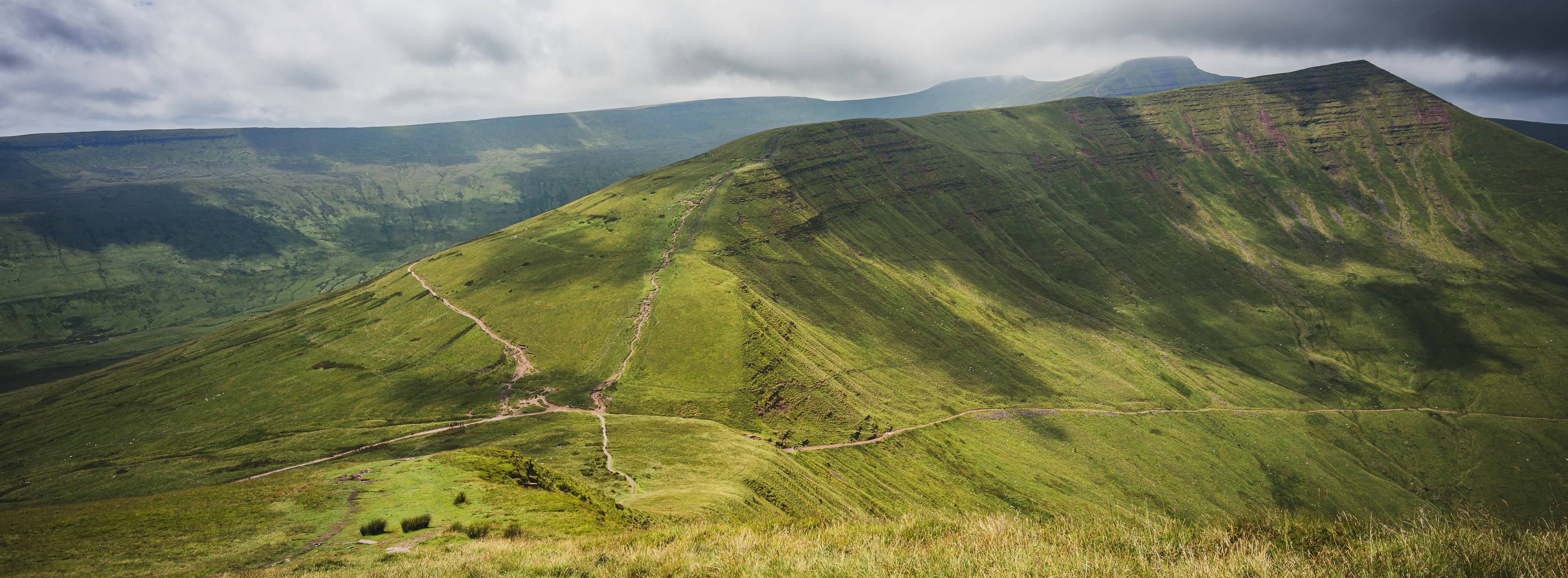 A view of a green mountain with a cloudy sky
