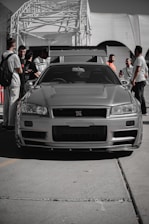 A silver car parked in front of a crowd of people