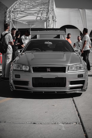 A silver car parked in front of a crowd of people