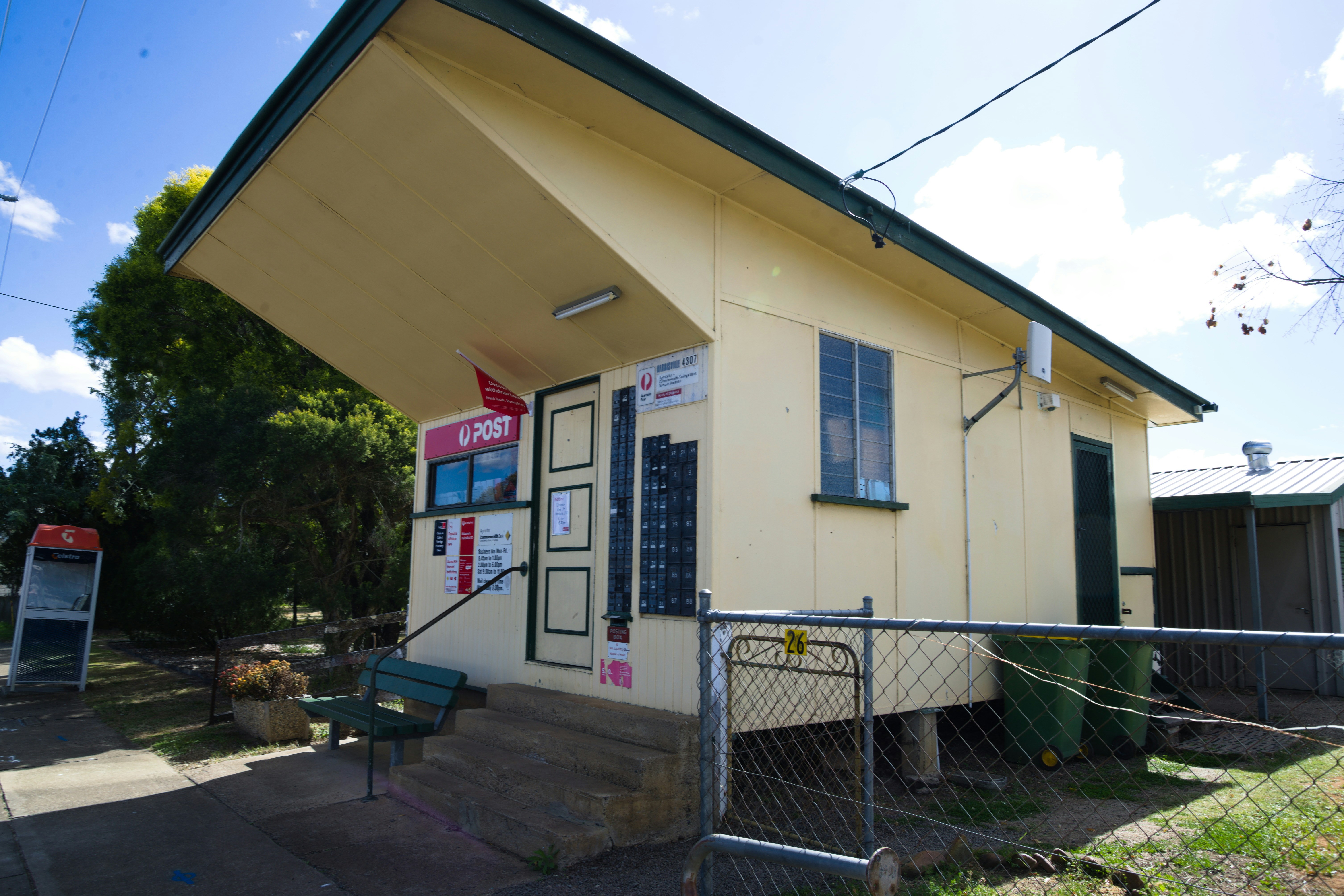 Um pequeno prédio amarelo com uma cerca de metal ao redor