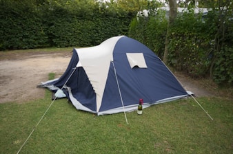 A blue and white tent sitting on top of a lush green field