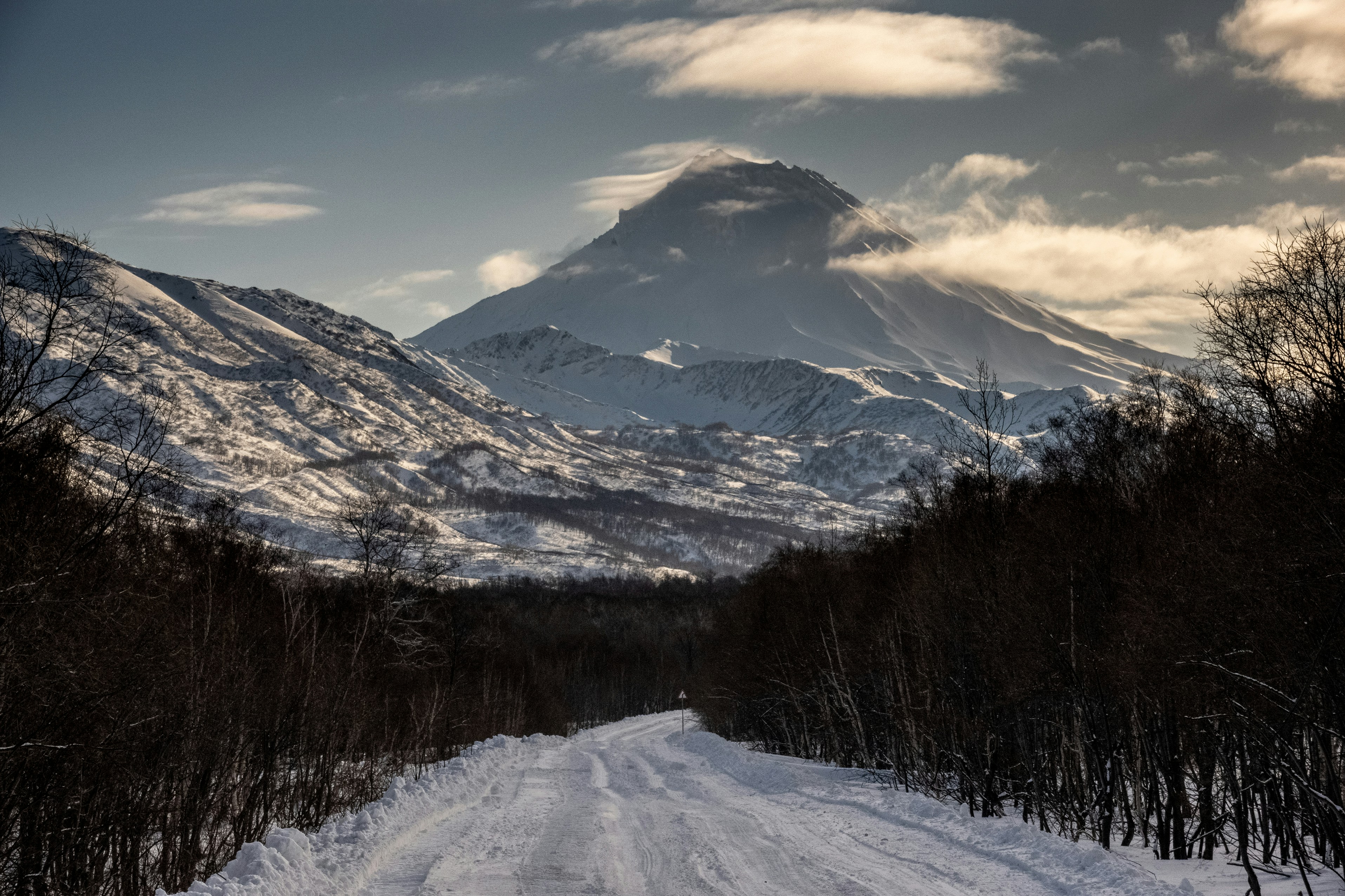 A snow covered road with a mountain in the background