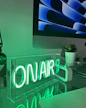 A desk with a computer monitor and a neon sign