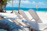 A couple of lawn chairs sitting on top of a sandy beach