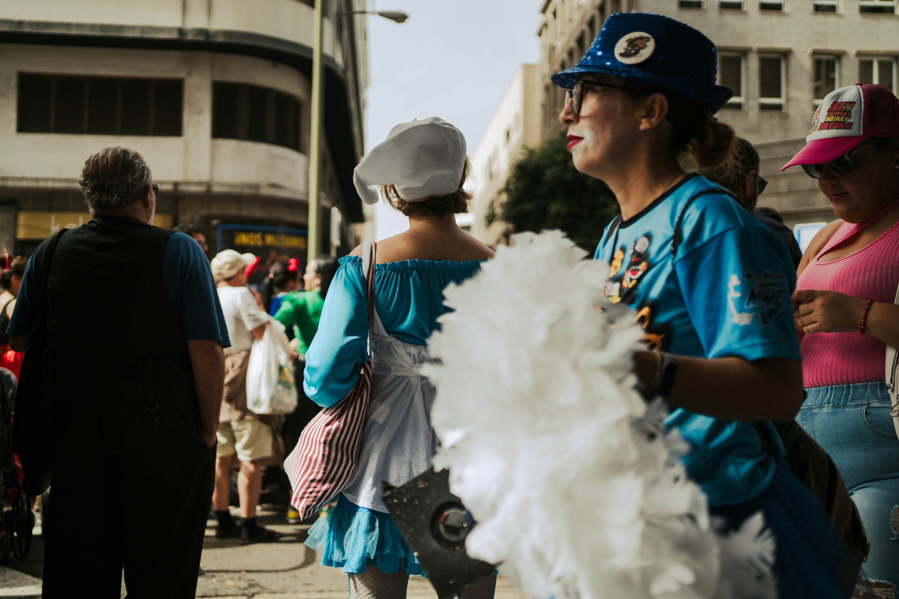 A group of people walking down a street next to tall buildings