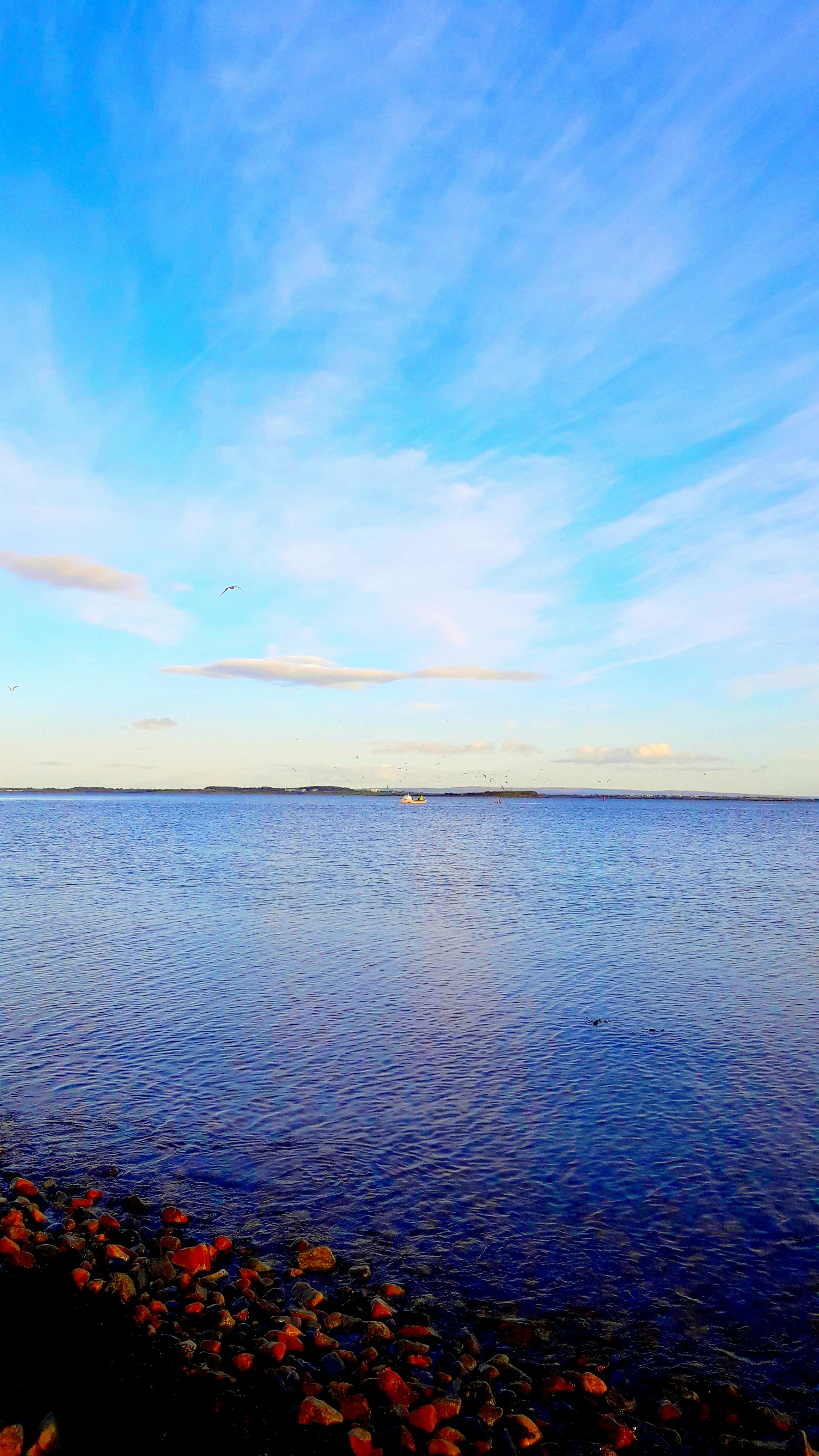 A body of water surrounded by rocks under a blue sky