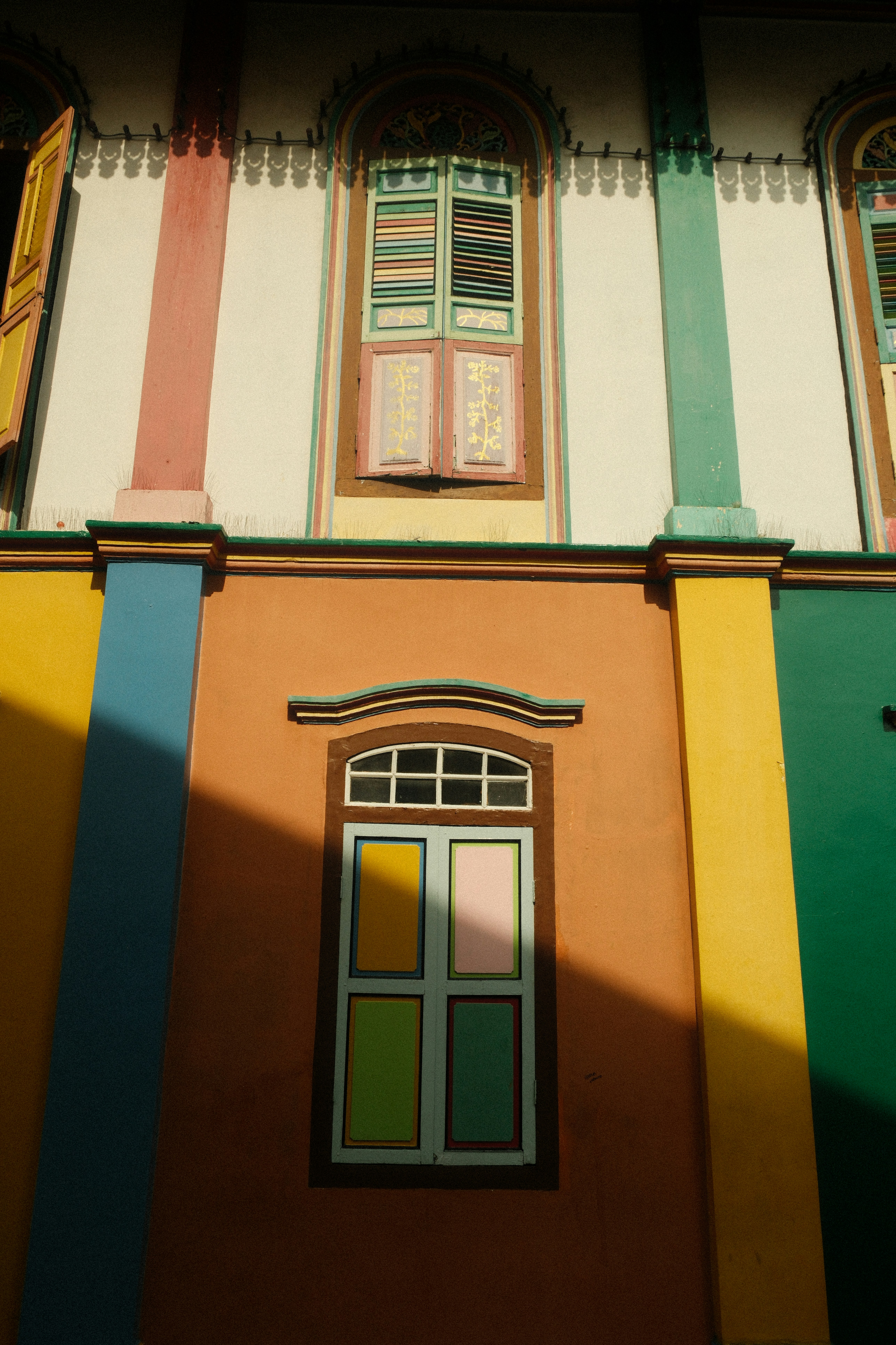 A multicolored building with a window and shutters