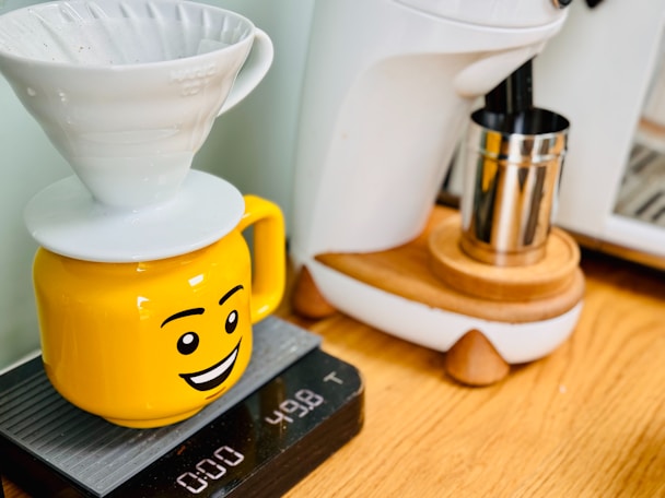 A yellow coffee pot sitting on top of a stack of books