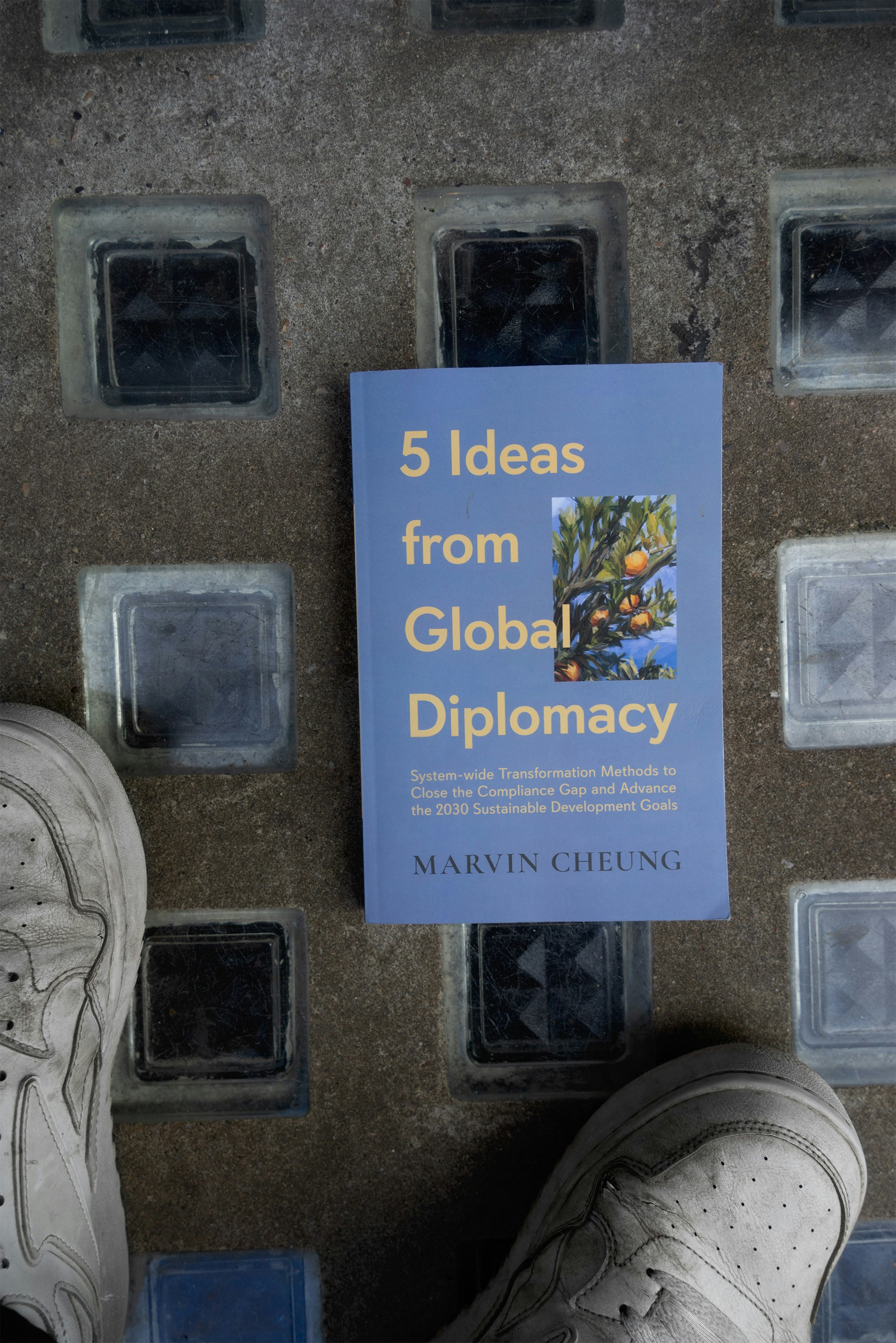 A book sitting on top of a sidewalk next to a pair of shoes