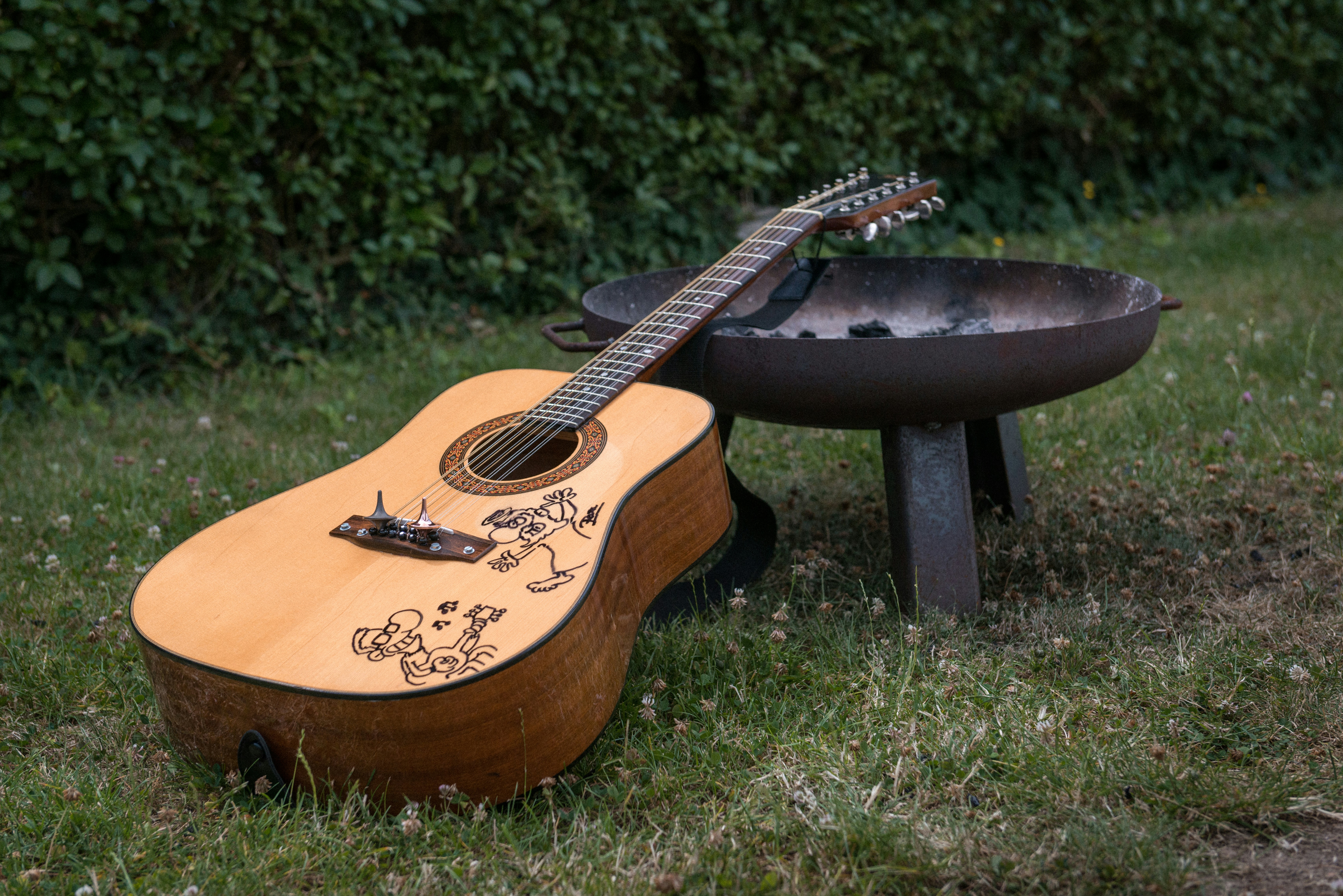 Une guitare posée dans l’herbe à côté d’un foyer