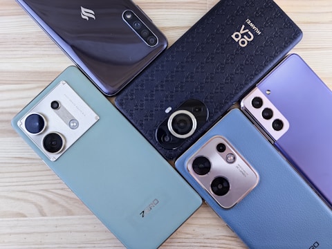 A group of four cell phones sitting on top of a wooden table