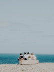 A group of people sitting on top of a sandy beach