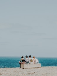 A group of people sitting on top of a sandy beach