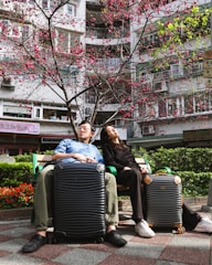 A man and woman sitting on a bench with their luggage