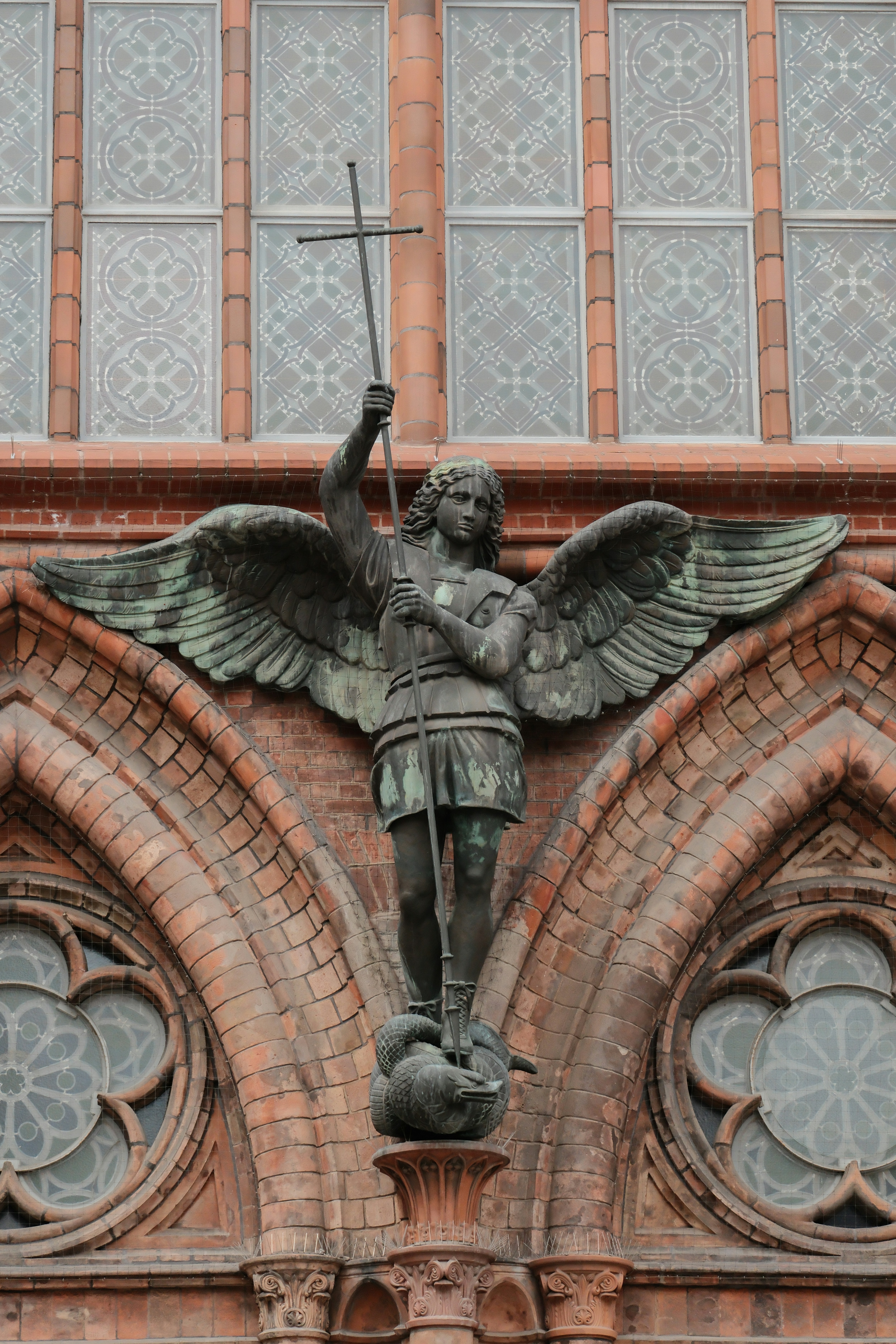 A statue of an angel holding a cross on top of a building - a-statue-of-an-angel-holding-a-cross-on-top-of-a-building-QCp_PxwnNDs