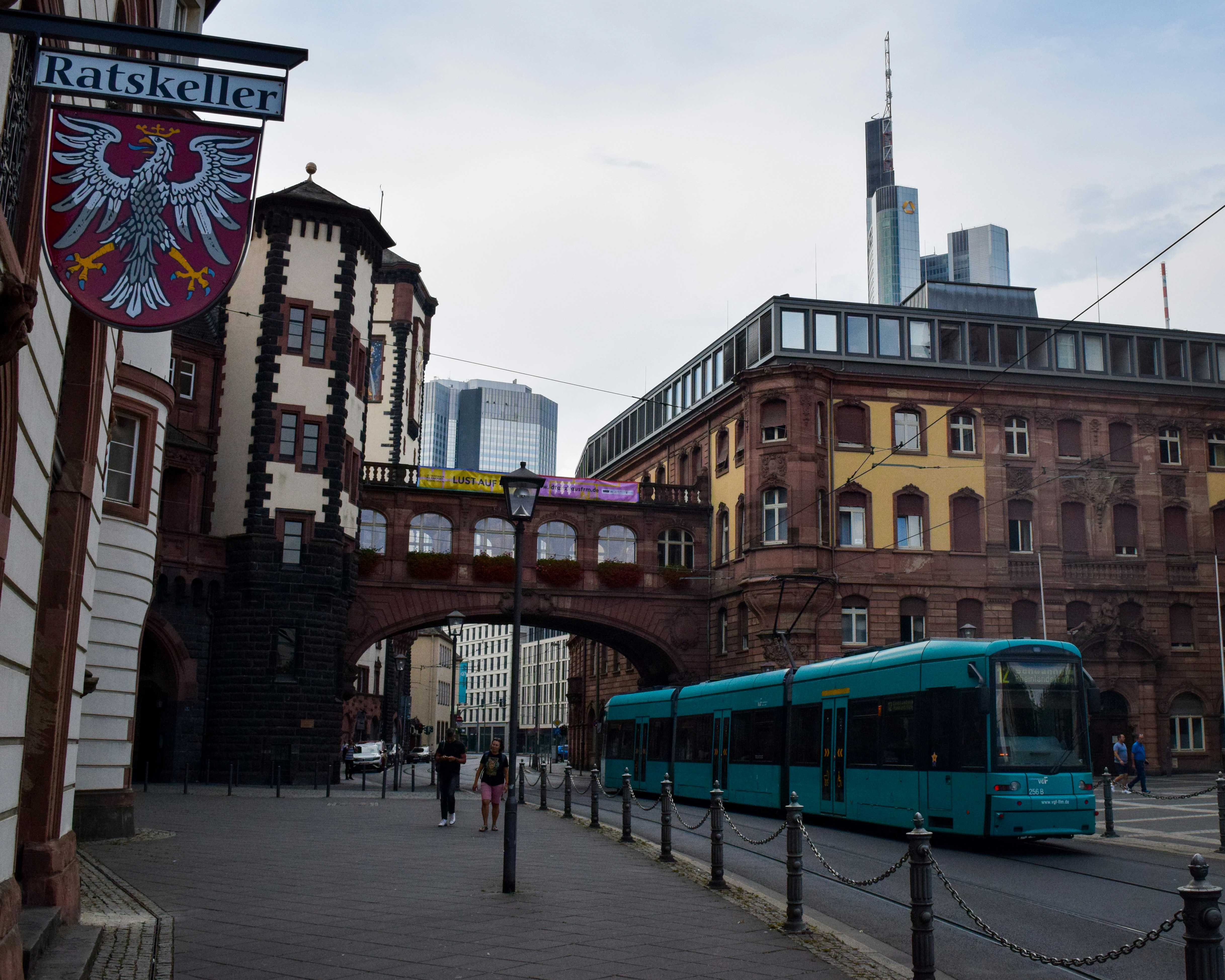 A blue bus driving down a street next to tall buildings