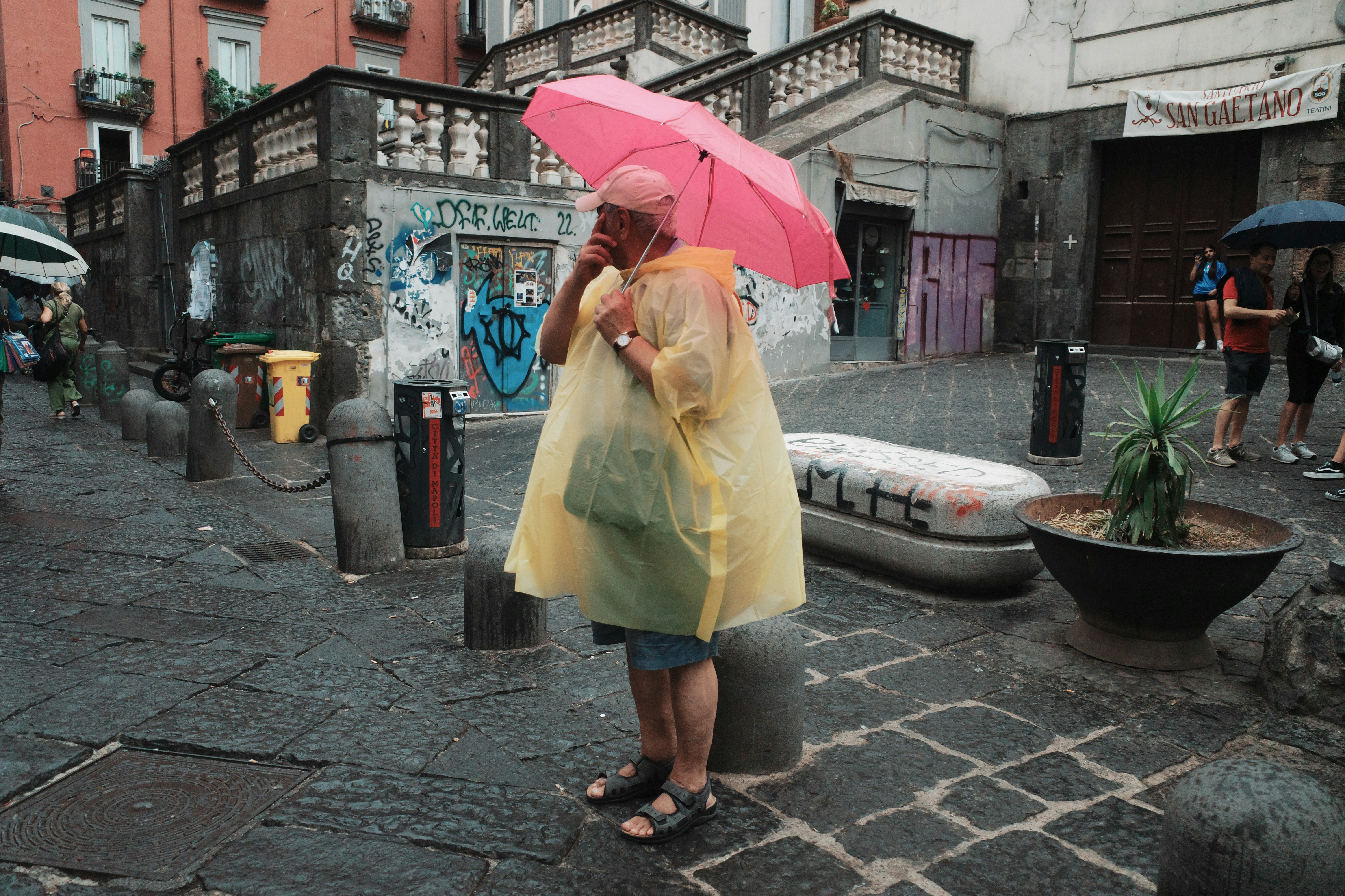 A woman in a yellow raincoat holding a pink umbrella
