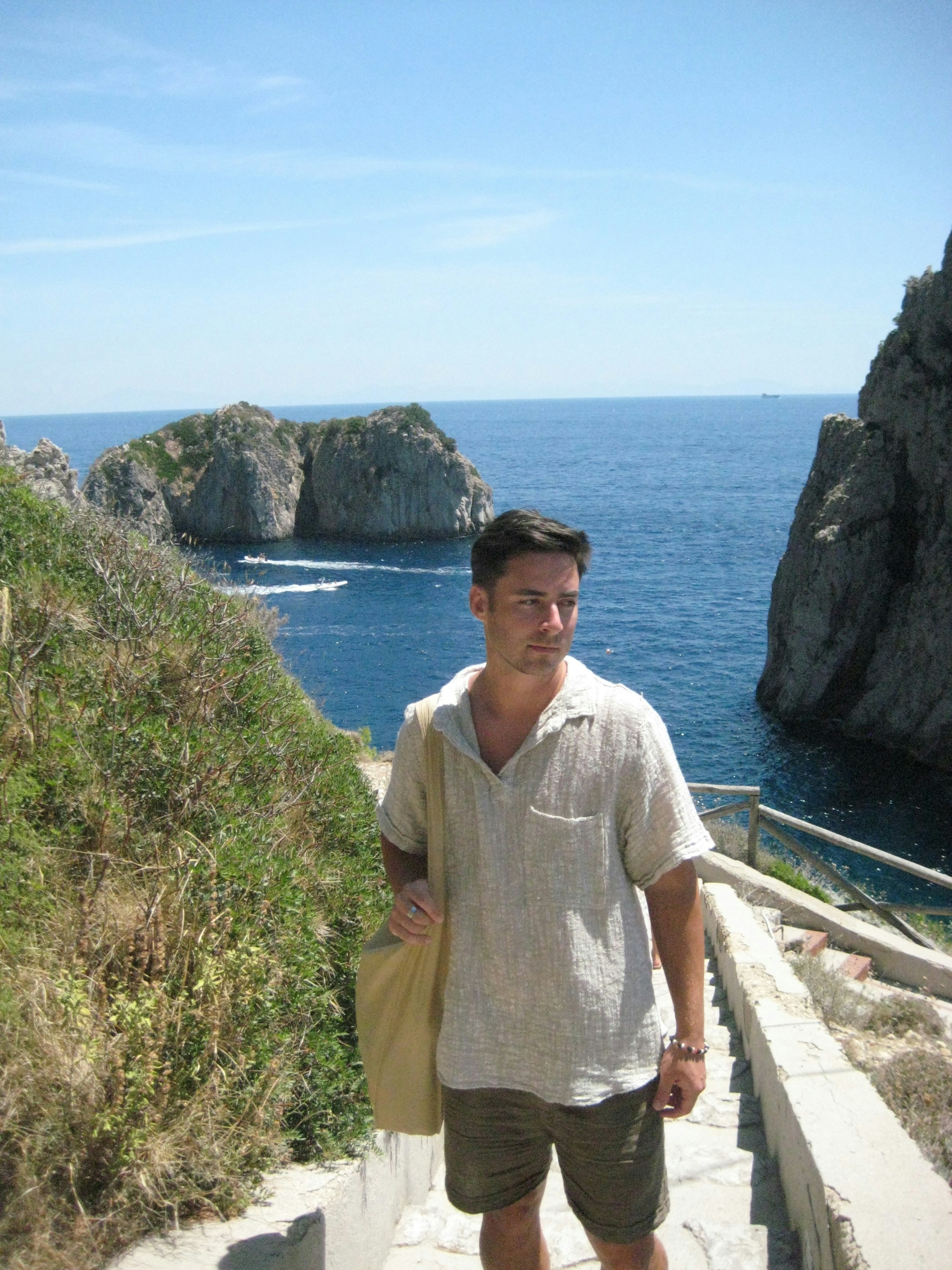 A man is standing on a stairway near the ocean