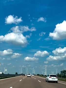 A car driving down a highway with windmills in the background