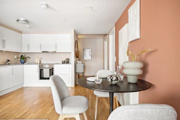 A living room with a table a chair and a refrigerator