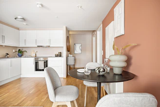 A living room with a table a chair and a refrigerator