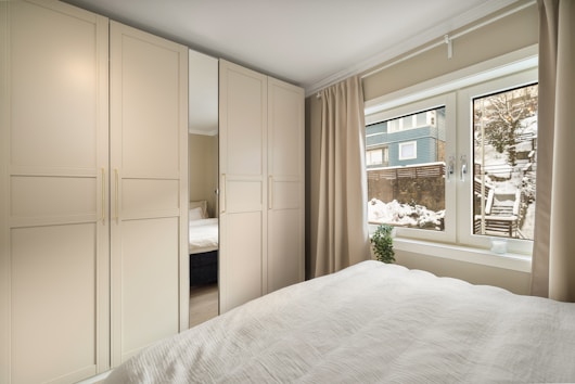 A bedroom with a white bed and a window