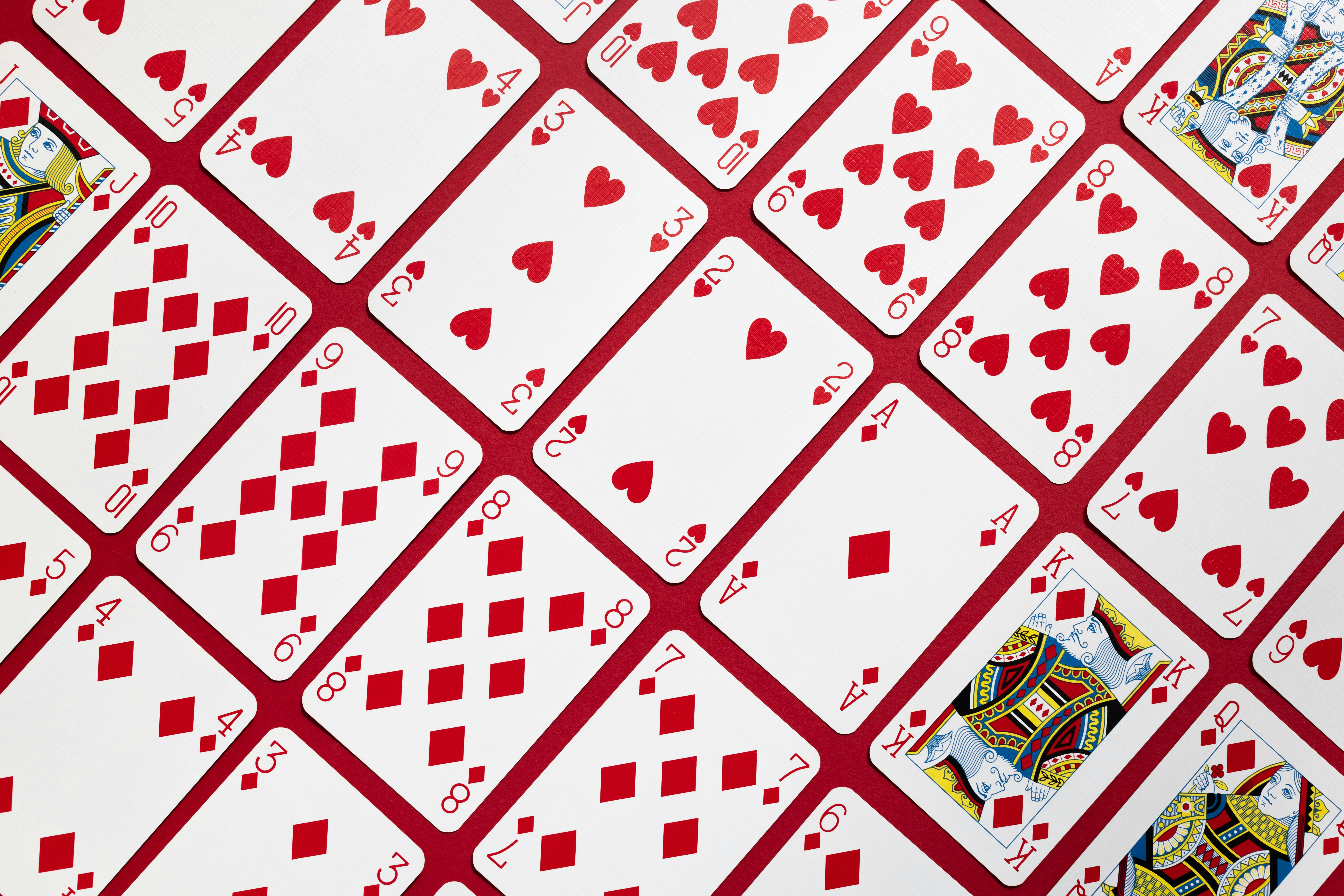 The hearts and diamonds from a pack of playing cards arranged diagonally against a red background.