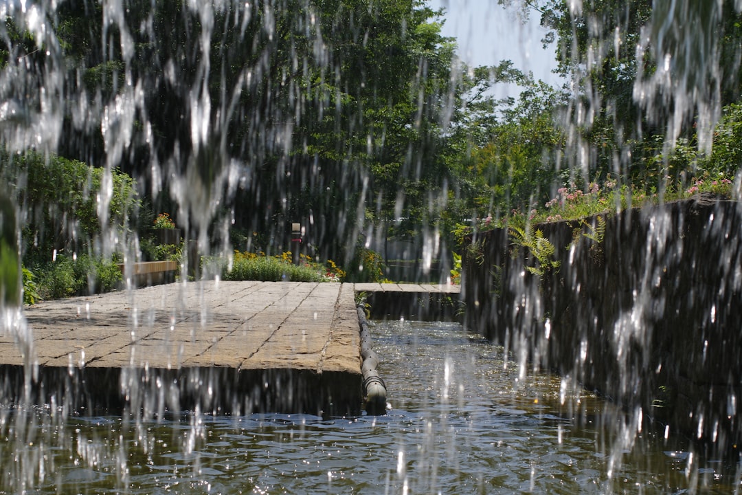 A large waterfall of water with trees in the background, Beautiful green and flower garden、新緑と美しい花が織りなす絶景 A superb view