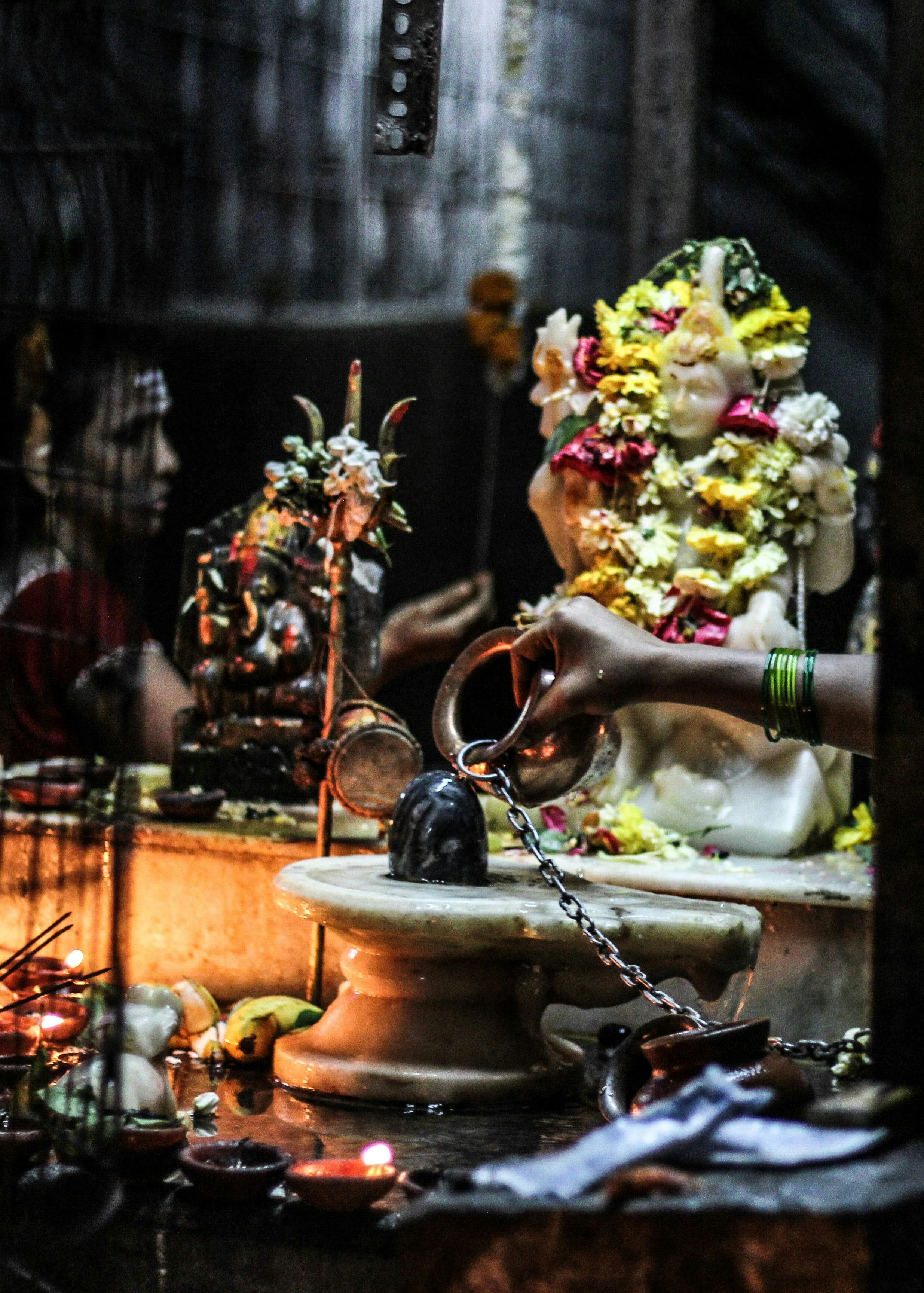 Sacred Shiva Abhishek ritual, priests pouring holy water on Shiva lingam, flowers and offerings, warm candlelight, devotional atmosphere