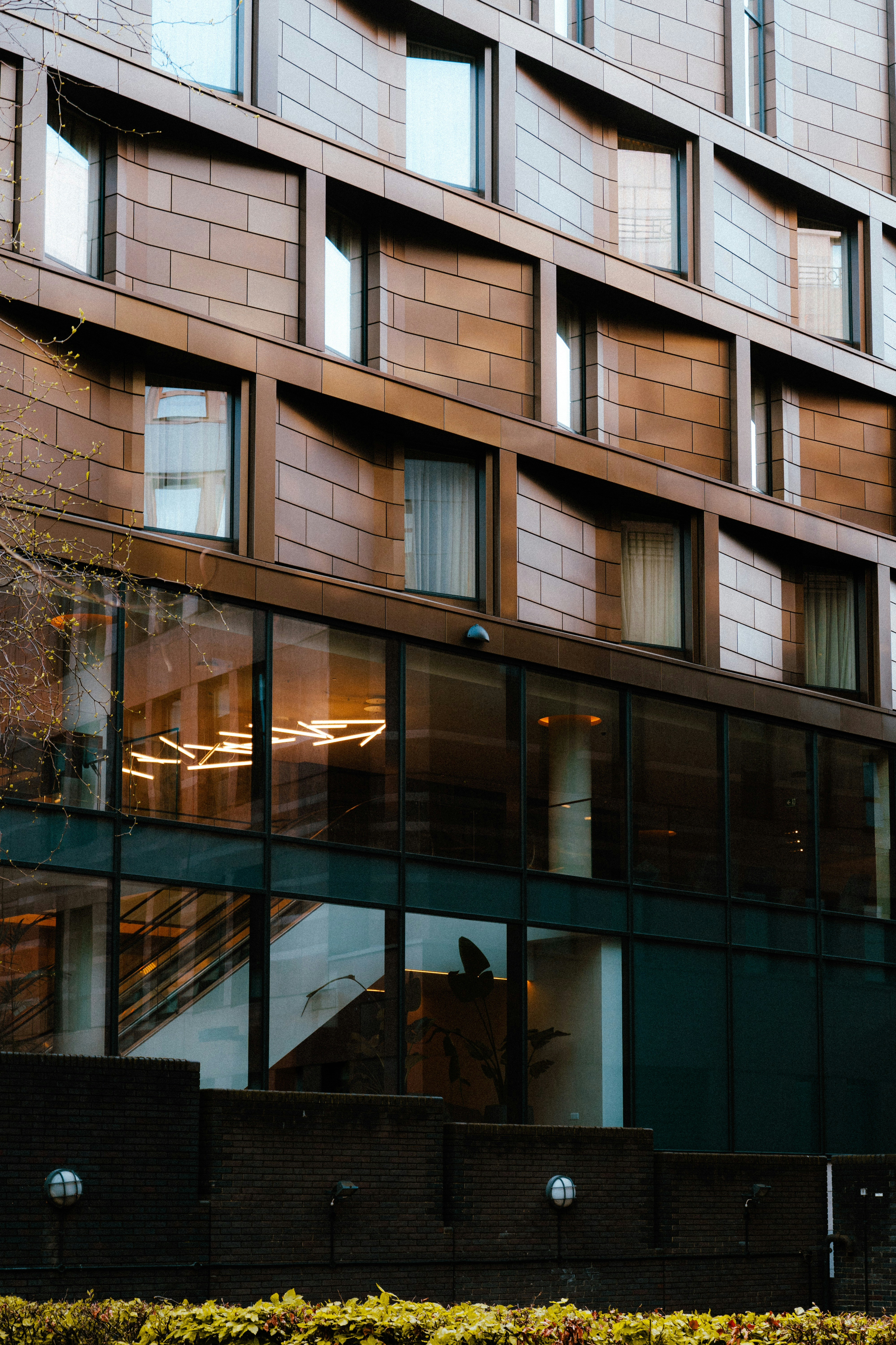 A tall building with lots of windows next to a sidewalk