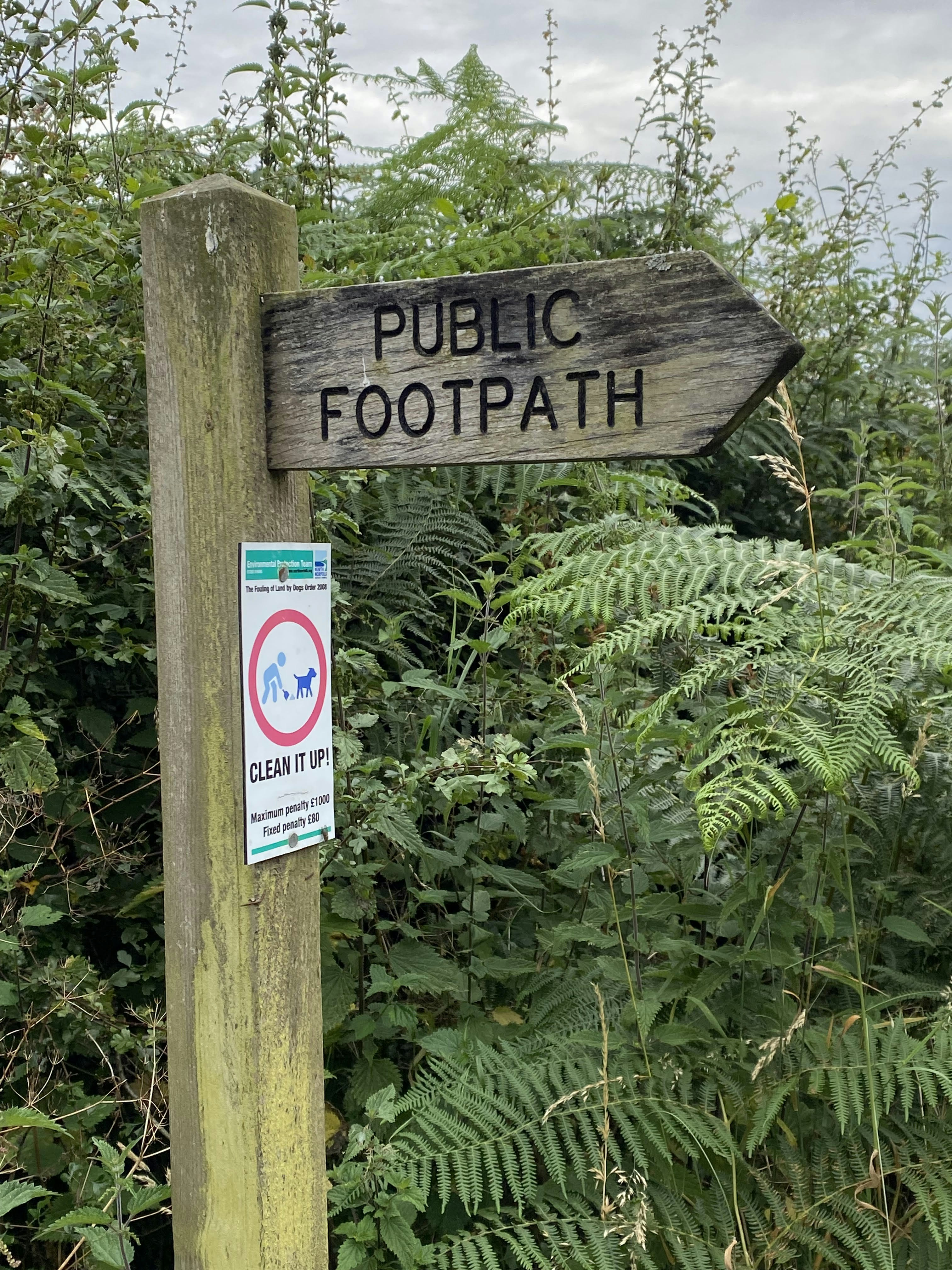 Un poteau en bois avec un panneau indiquant sentier public