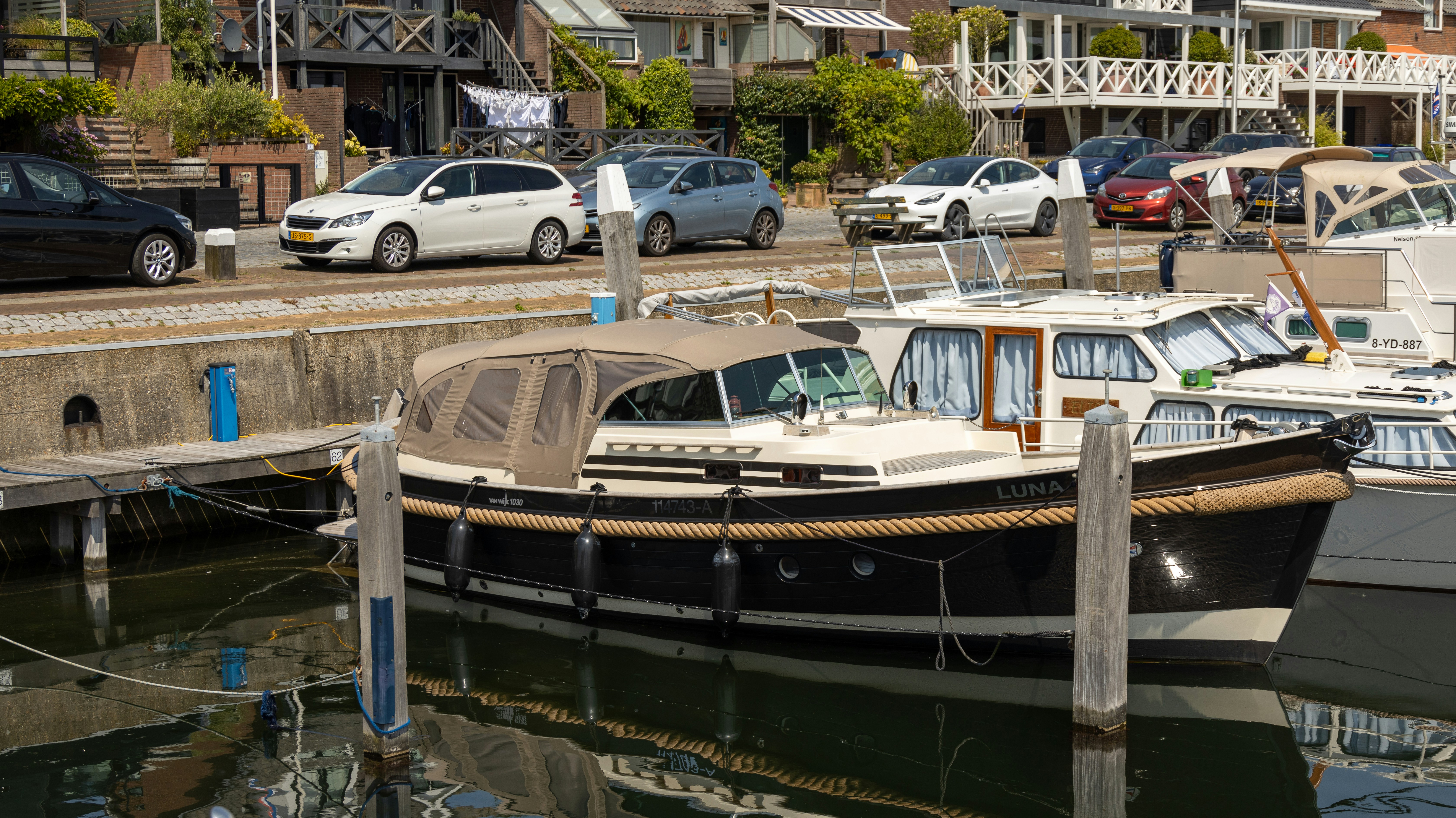 Yacht a motore ormeggiati in un porto turistico fiancheggiato da case residenziali.