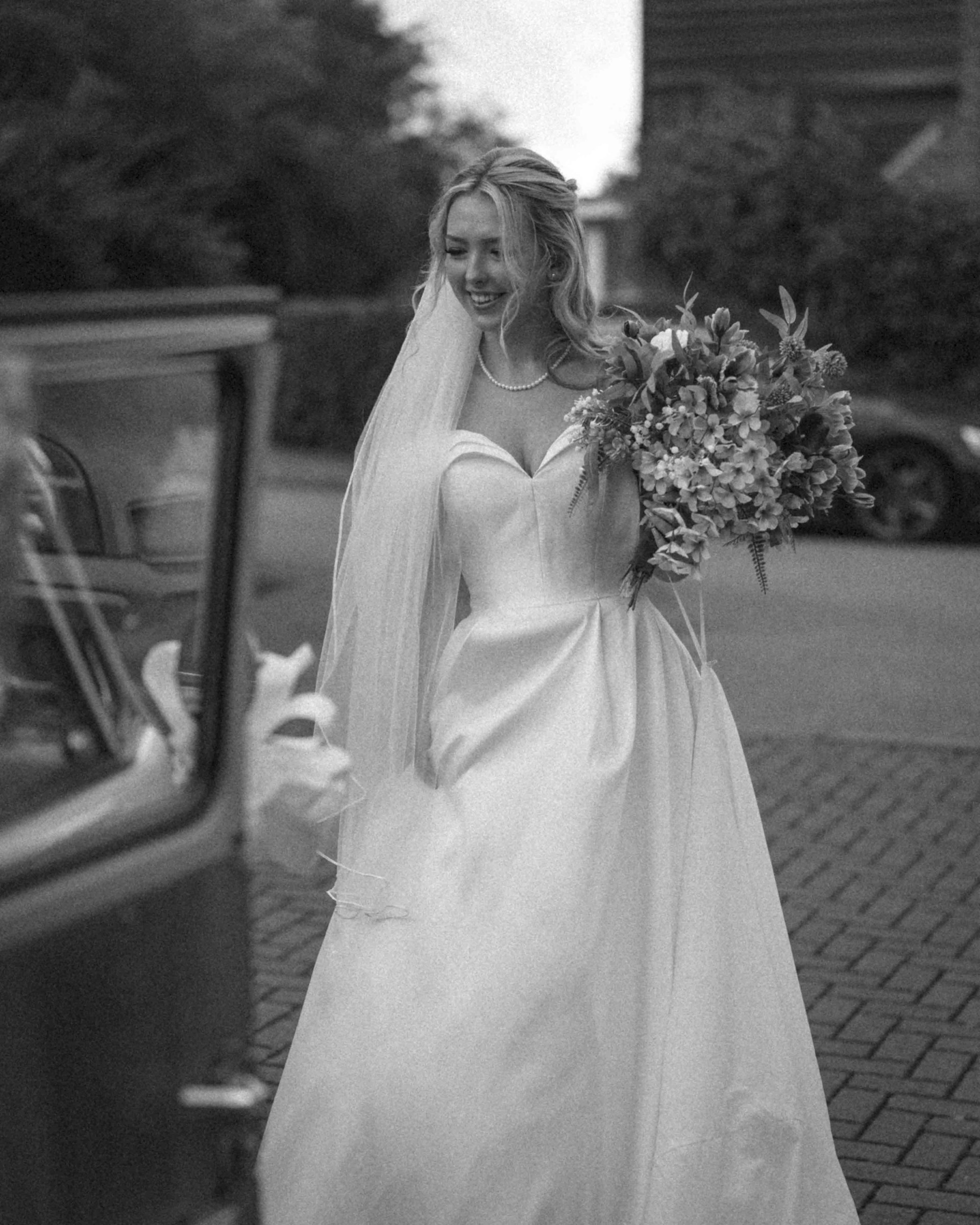 A woman in a wedding dress standing next to a car