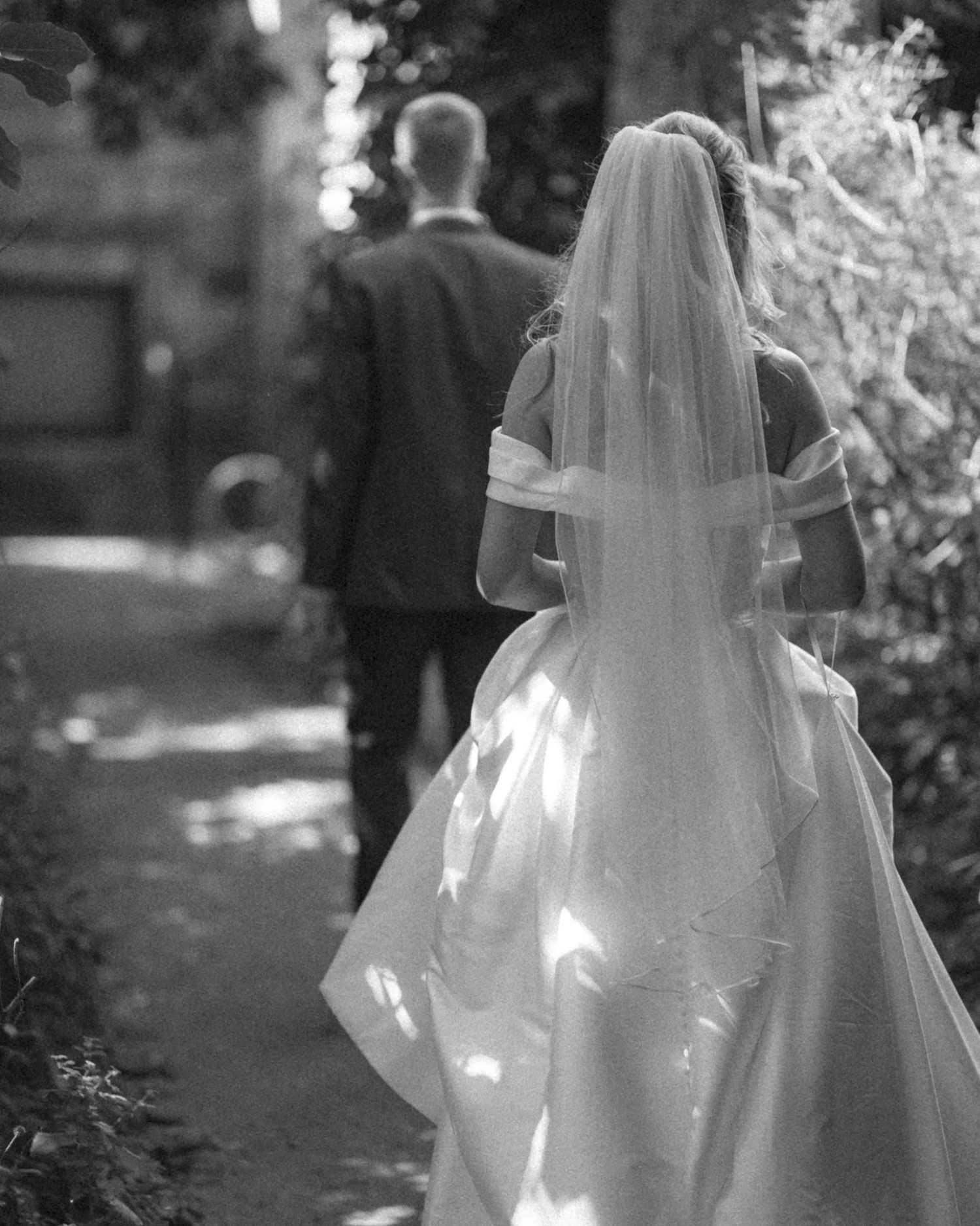 A bride walking away down a garden path, her train on the gravel