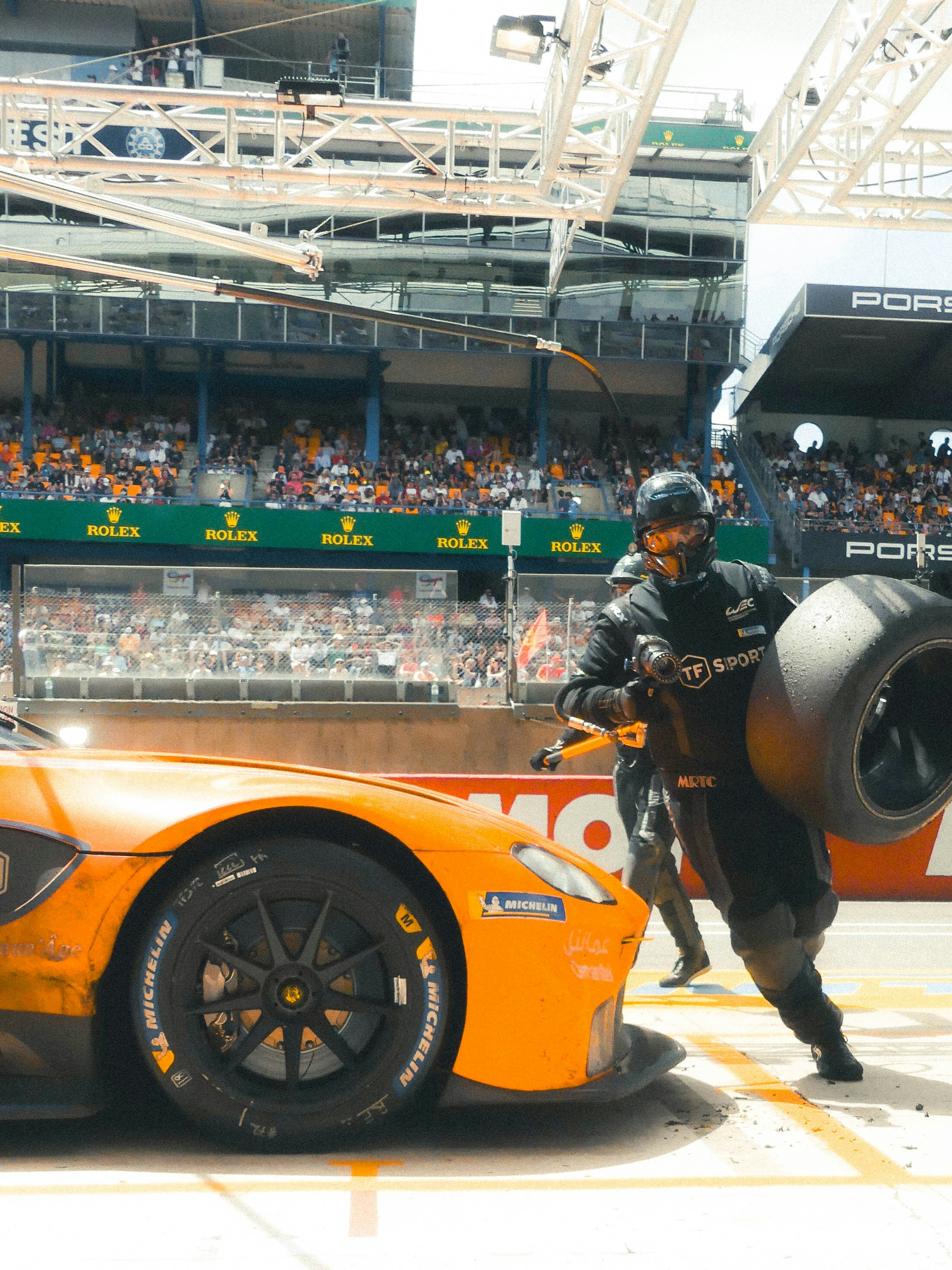 A man standing next to an orange sports car