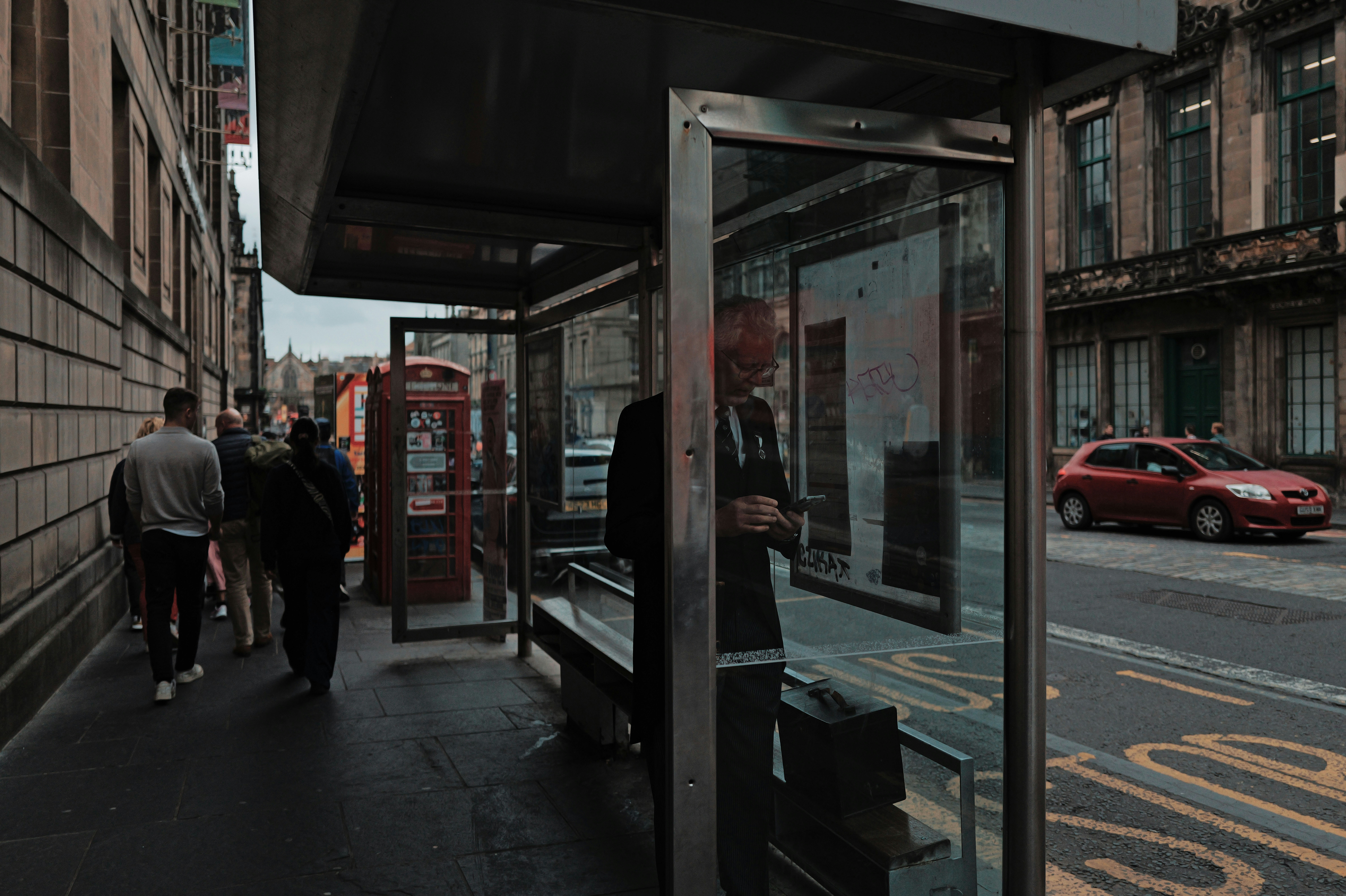Un groupe de personnes marchant sur un trottoir à côté d’un arrêt de bus
