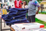 A group of people standing around a table with a bunch of shirts on it