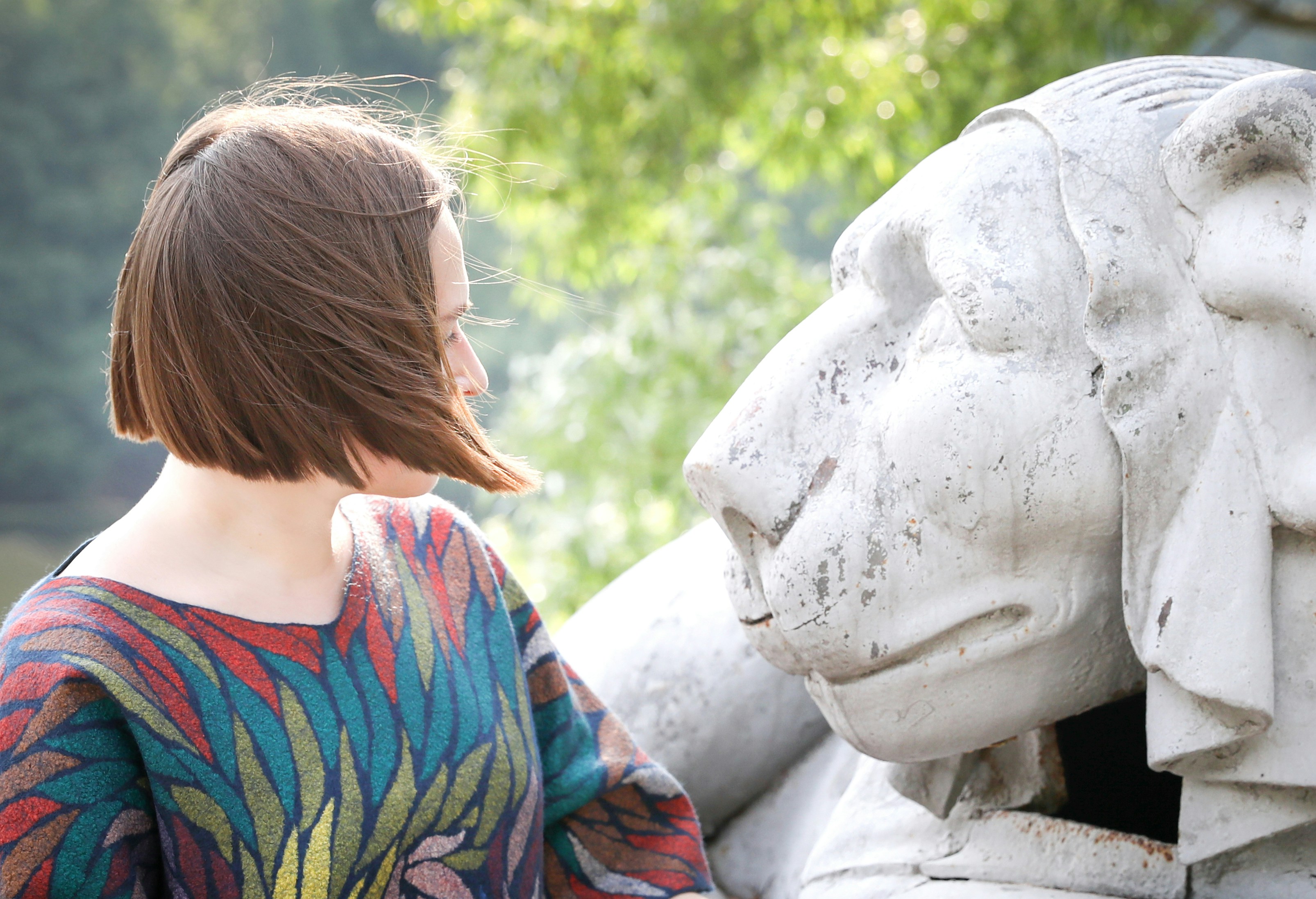 A woman standing next to a statue of a dog