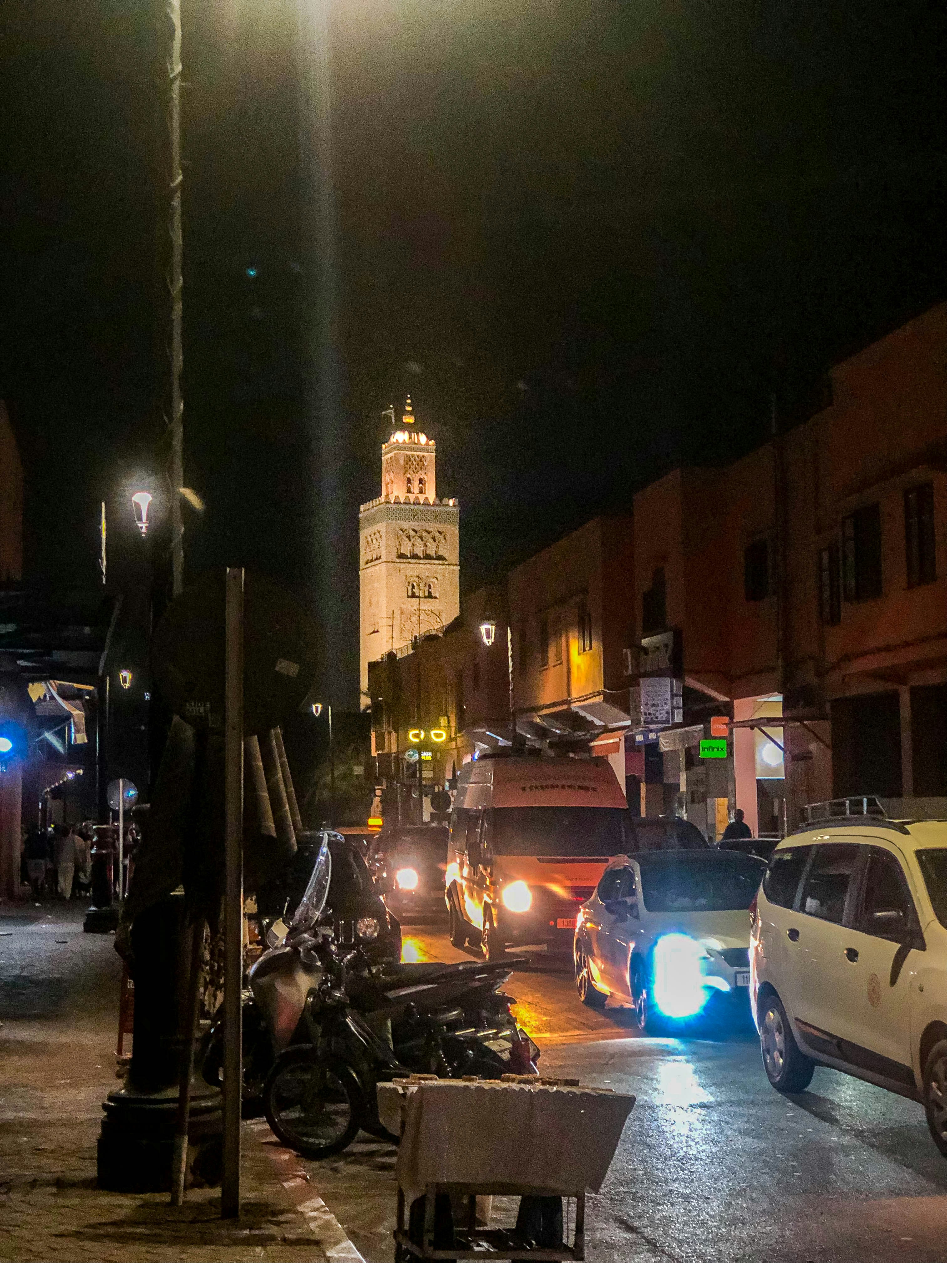 A city street at night with cars and motorcycles