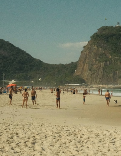 A group of people on a beach with a mountain in the background