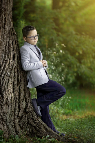 A man in a suit leaning against a tree