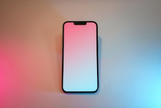 A pink and white cell phone sitting on top of a table