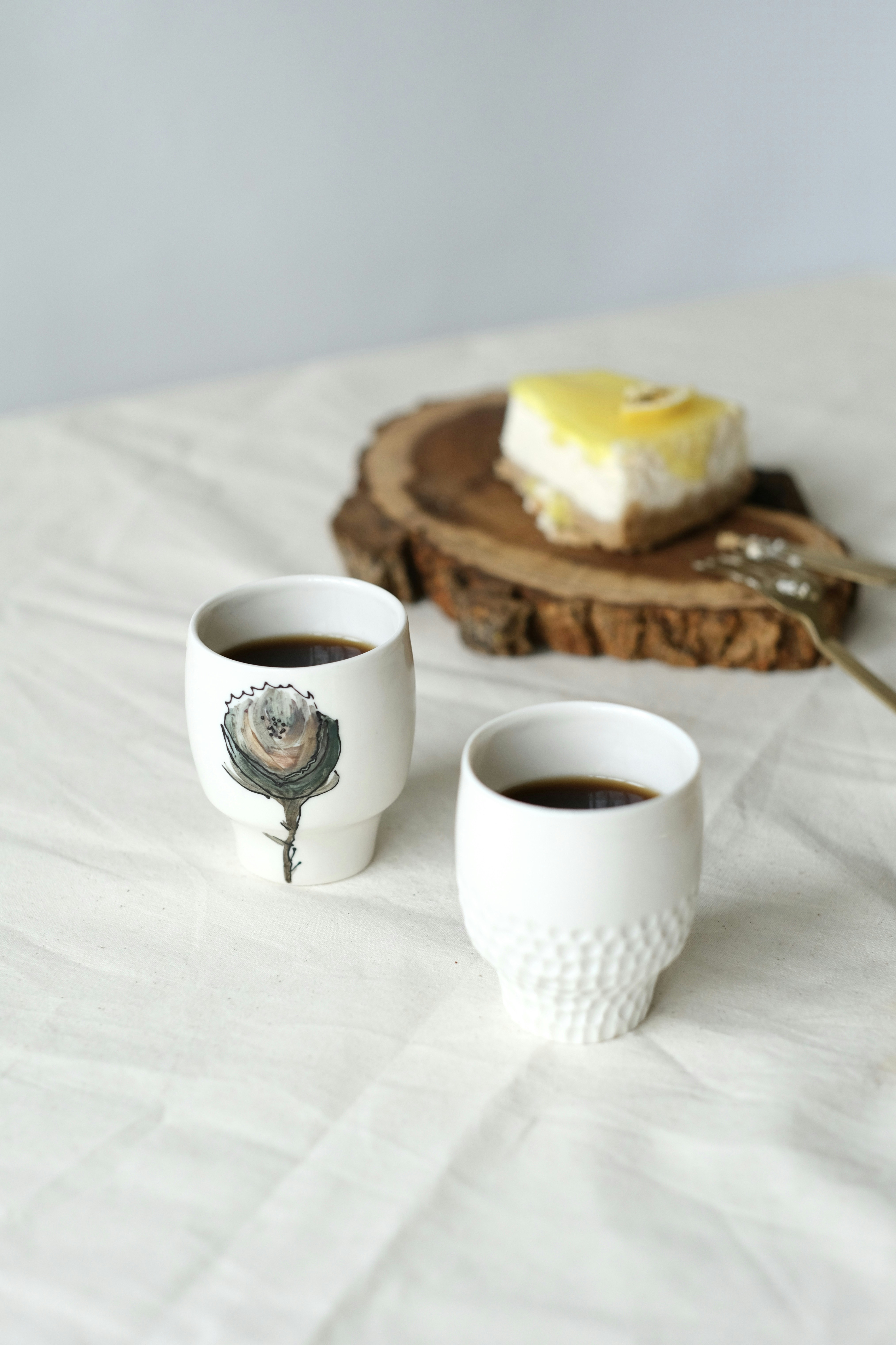 Two cups of coffee sit on a bed