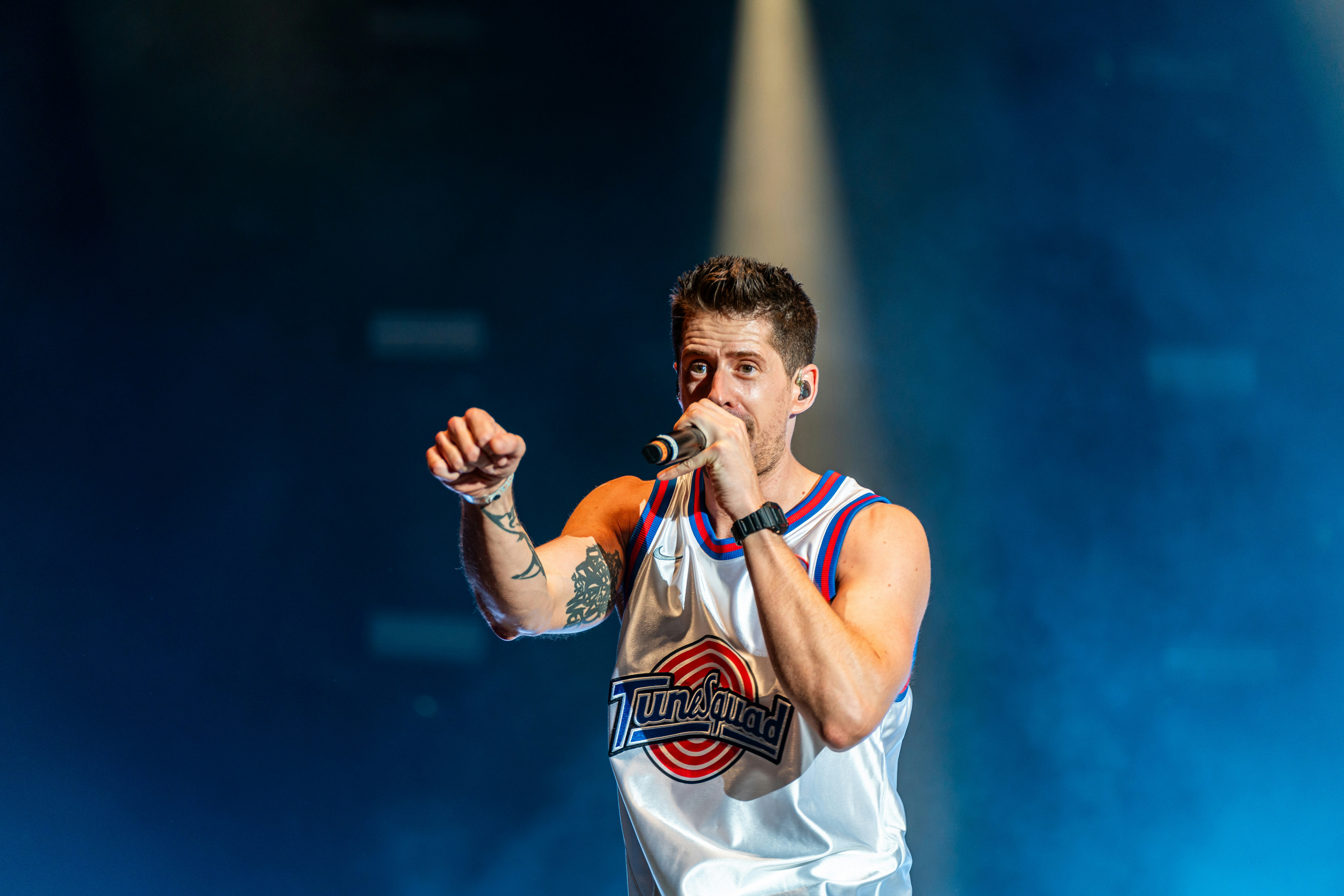 A male in a white shirt and a microphone