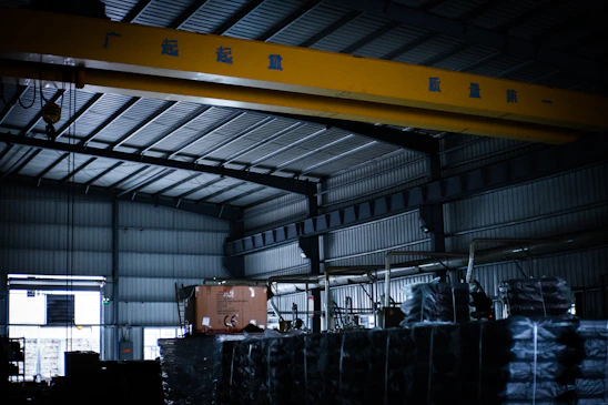 A large crane in a warehouse with lots of pallets