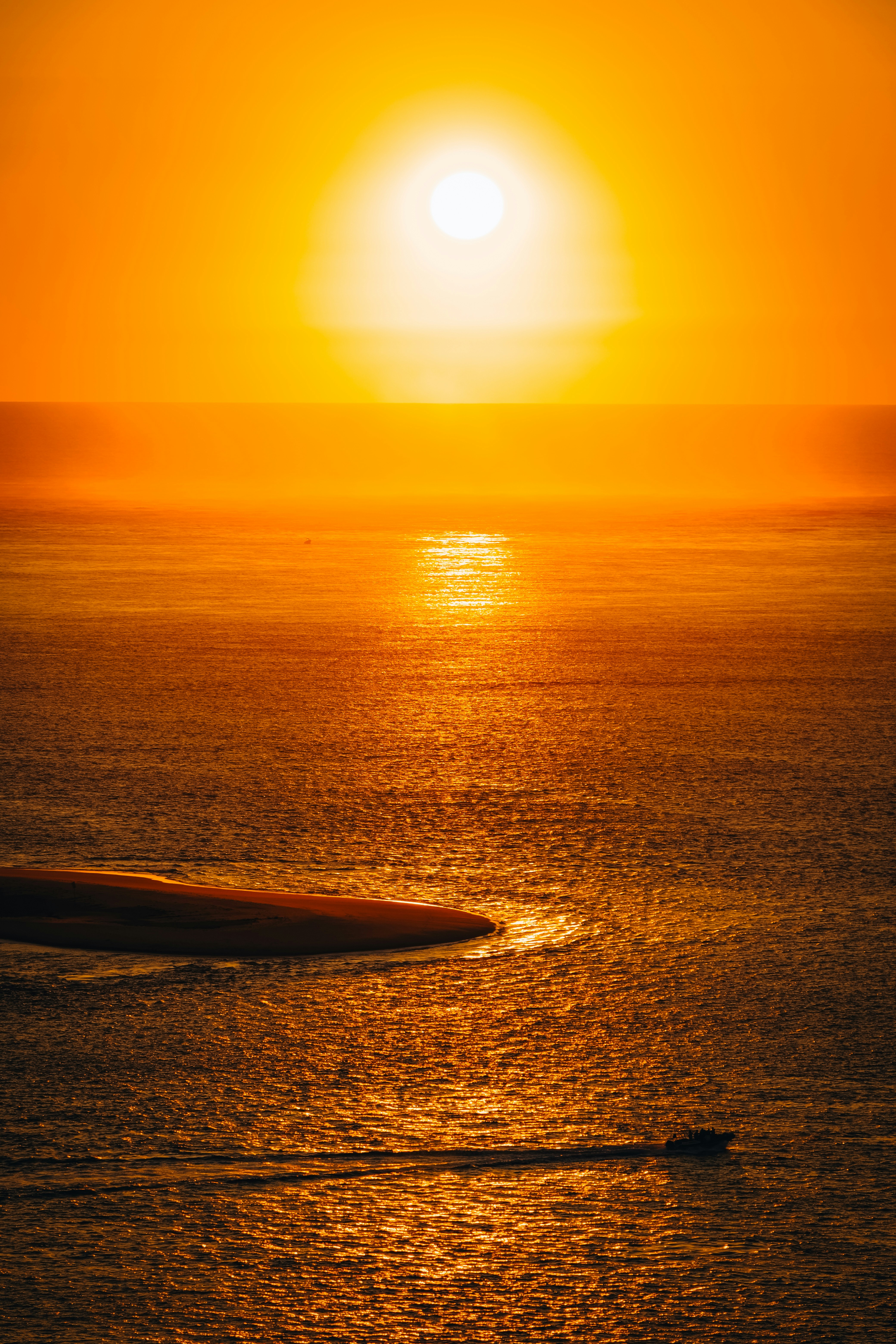 Die Sonne geht über dem Ozean unter, mit einem Boot im Wasser