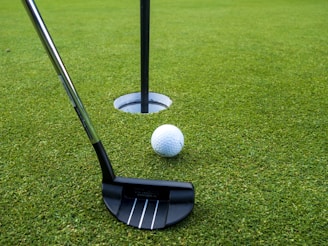 A golf putt and a golf ball on a putting green