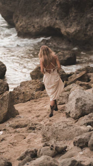 A little girl walking on a rocky beach next to the ocean